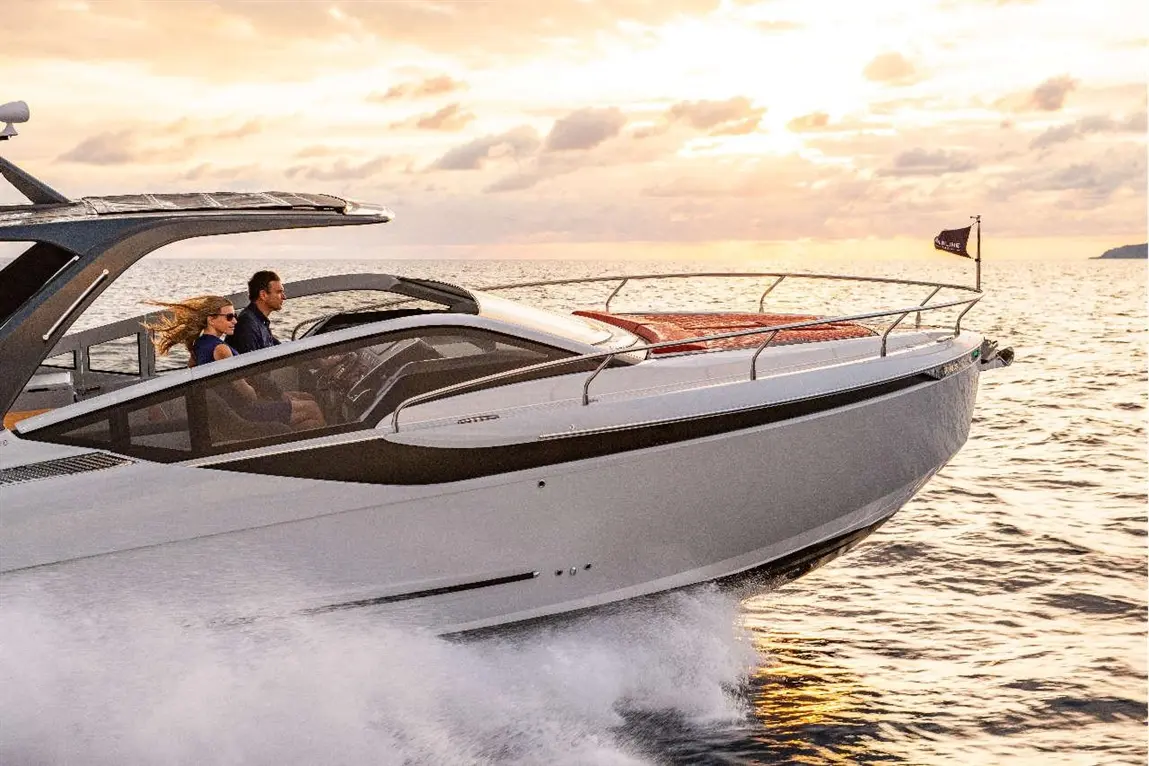 A couple drives a sleek motorboat on a sunset-lit ocean, highlighting adventure and relaxation on the water.